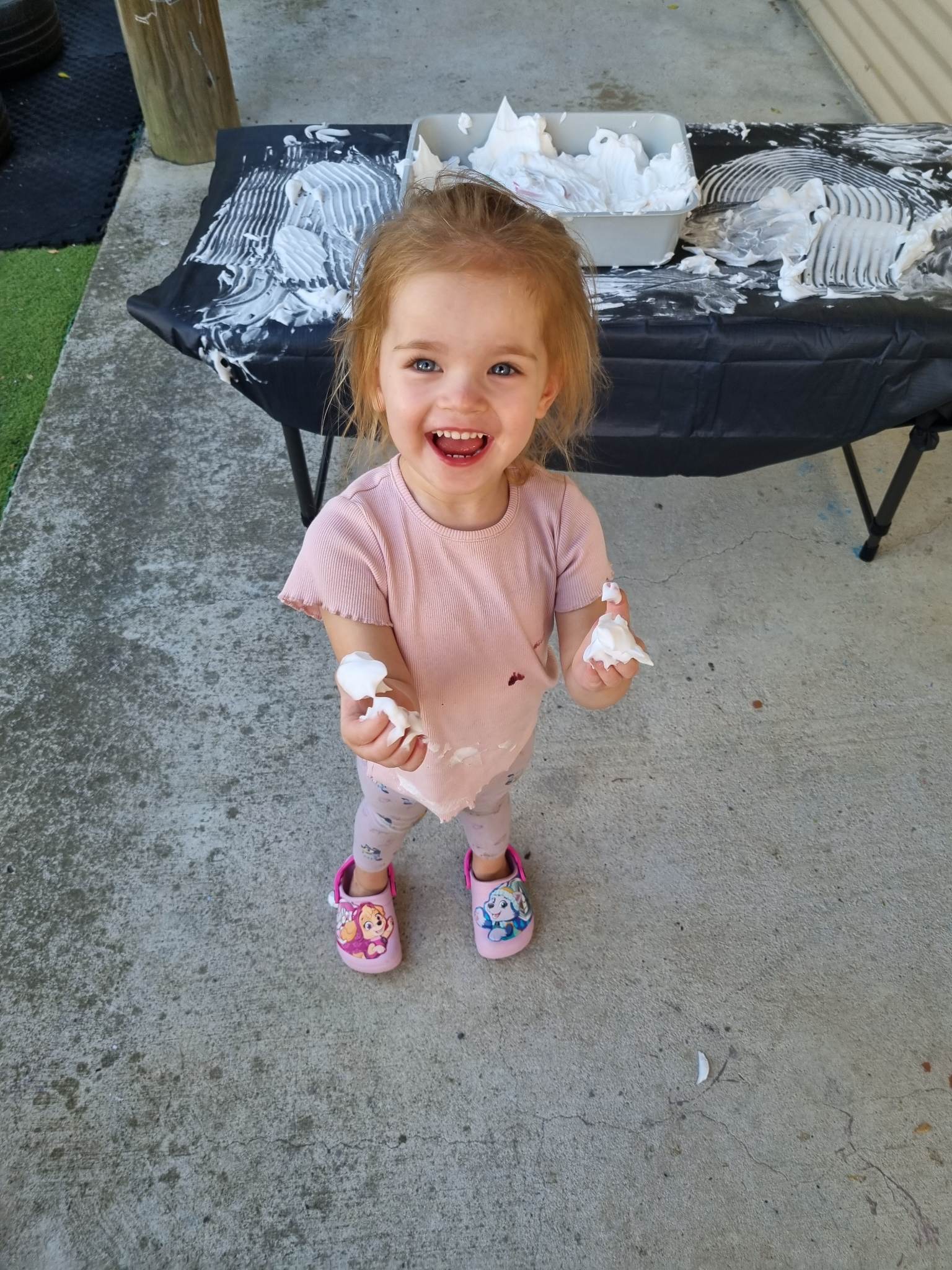 Smiling child playing with shaving foam at kids class